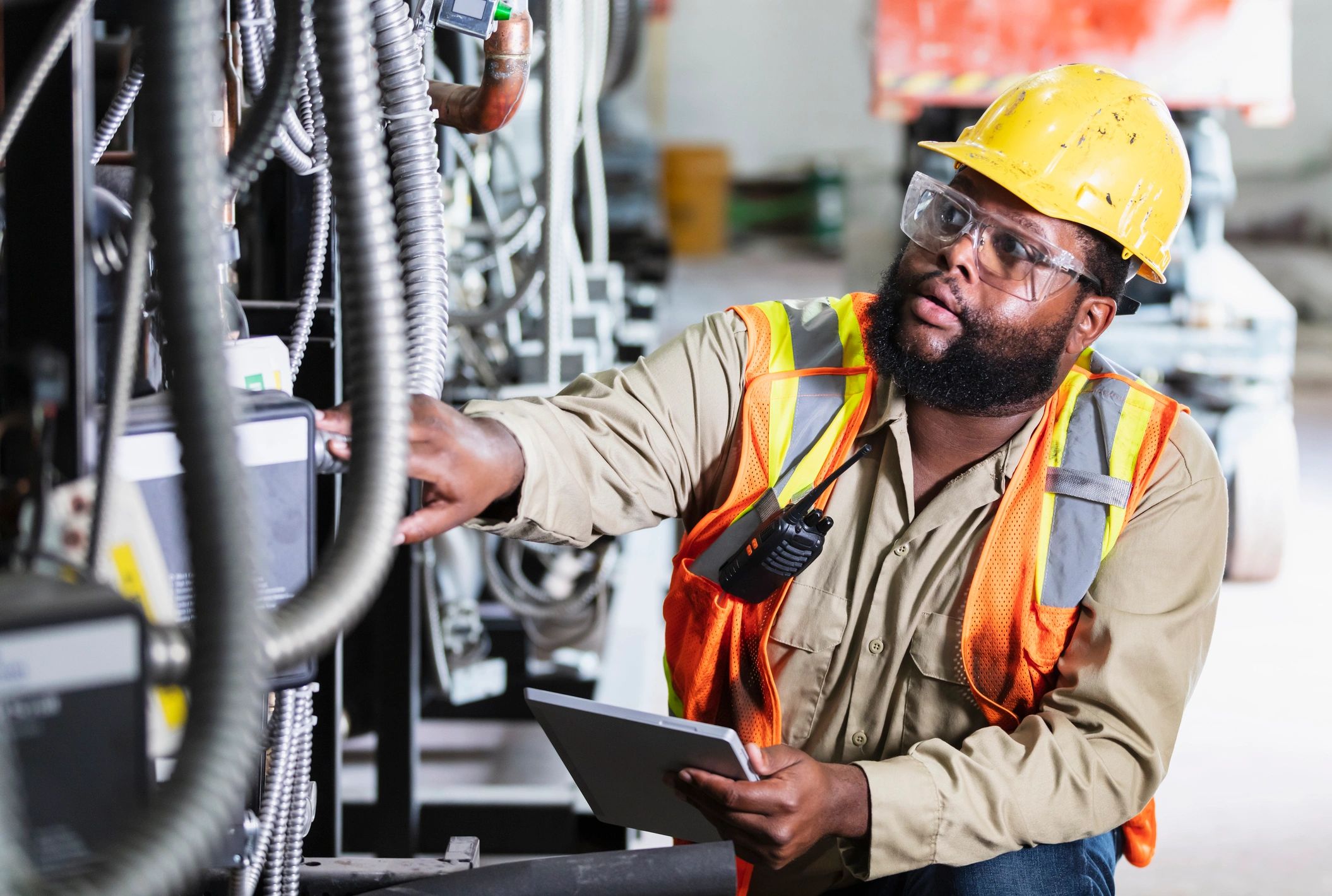 Worker inspecting industrial equipment with safety gear