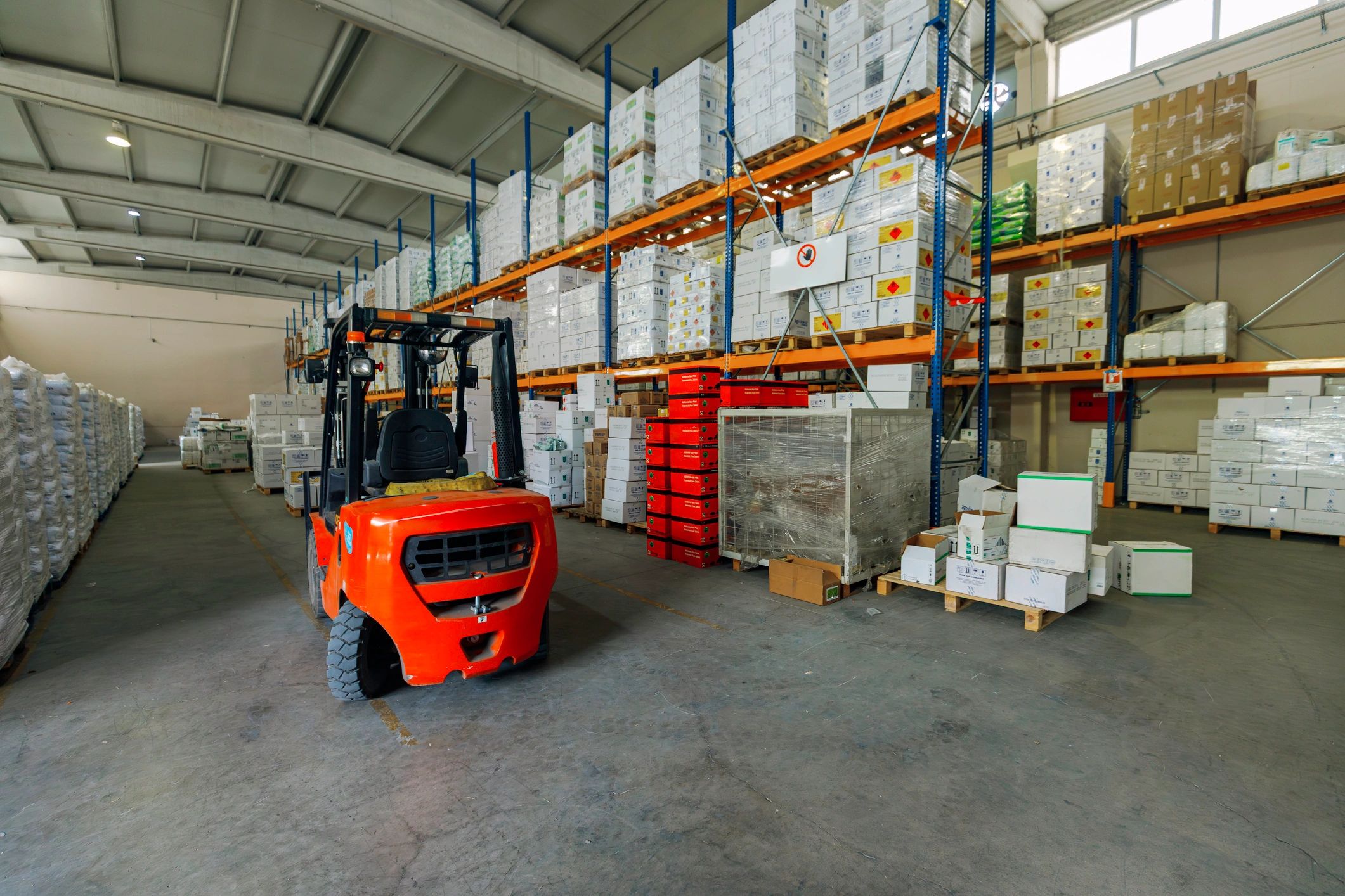 Forklift in a warehouse aisle with stacked goods
