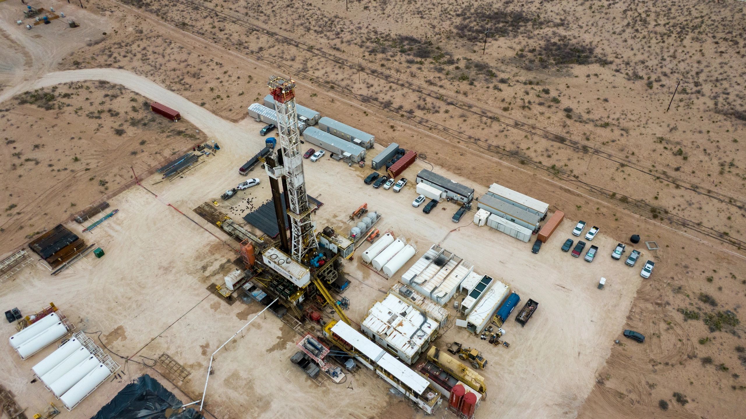 Onshore oil facility with drilling derrick and storage tanks
