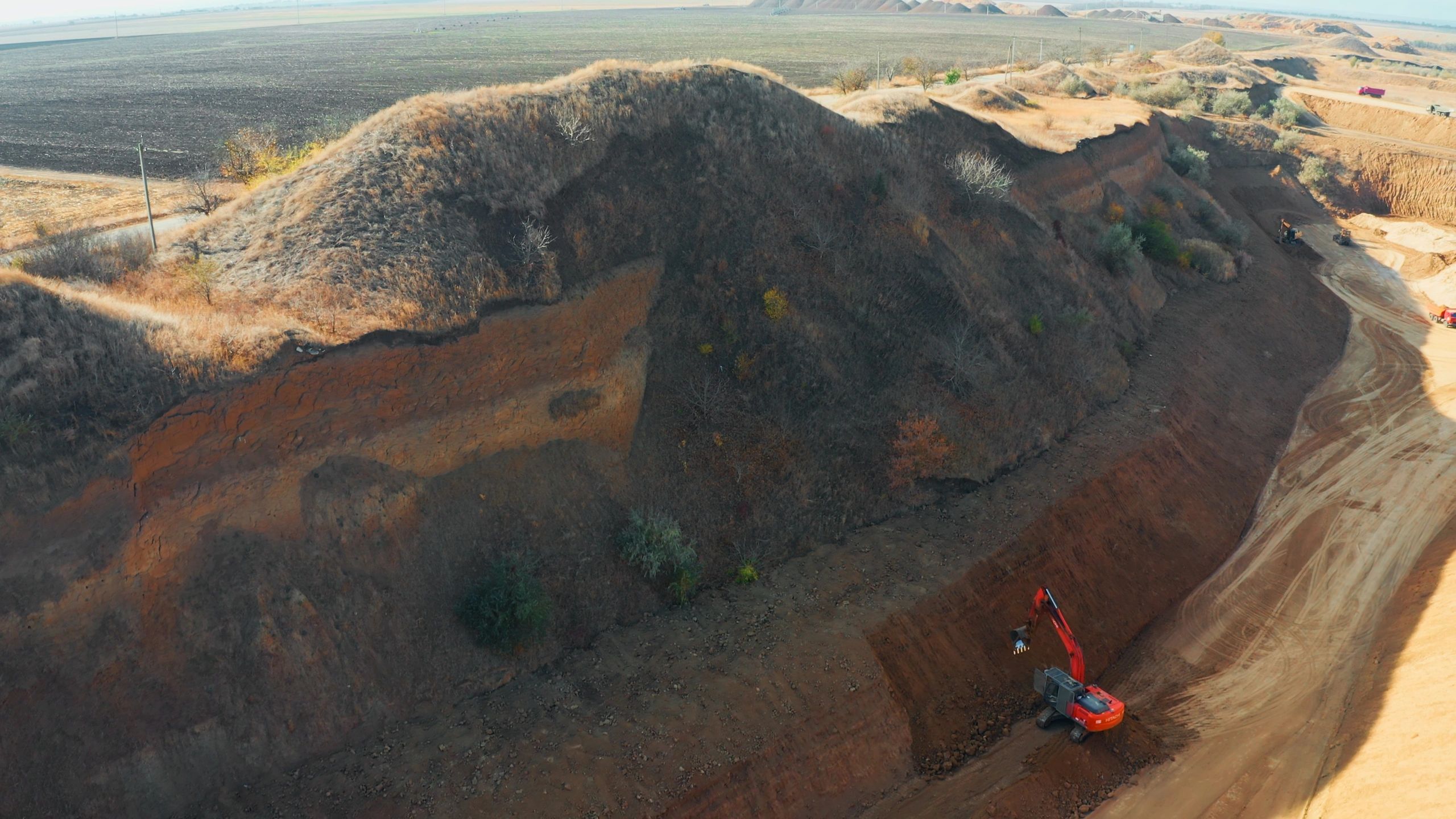 Excavator digging soil in large open pit quarry